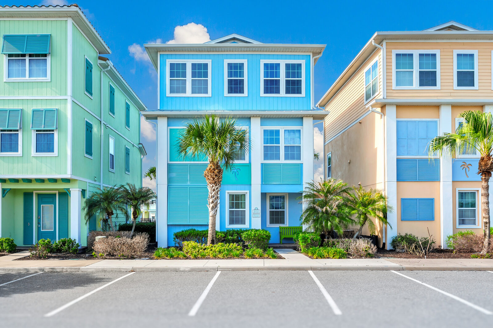 Turquoise three-story cottage with palm trees out front