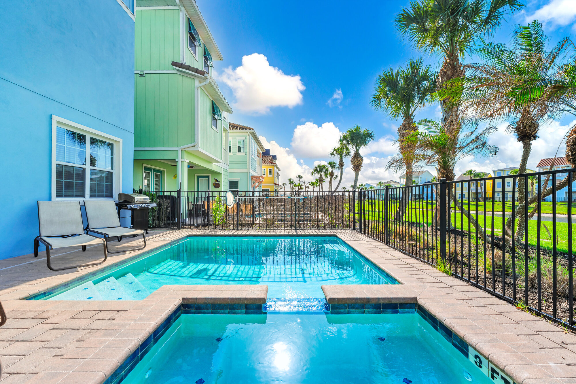 The cottage's private heated pool and spa with palms and a lake behind